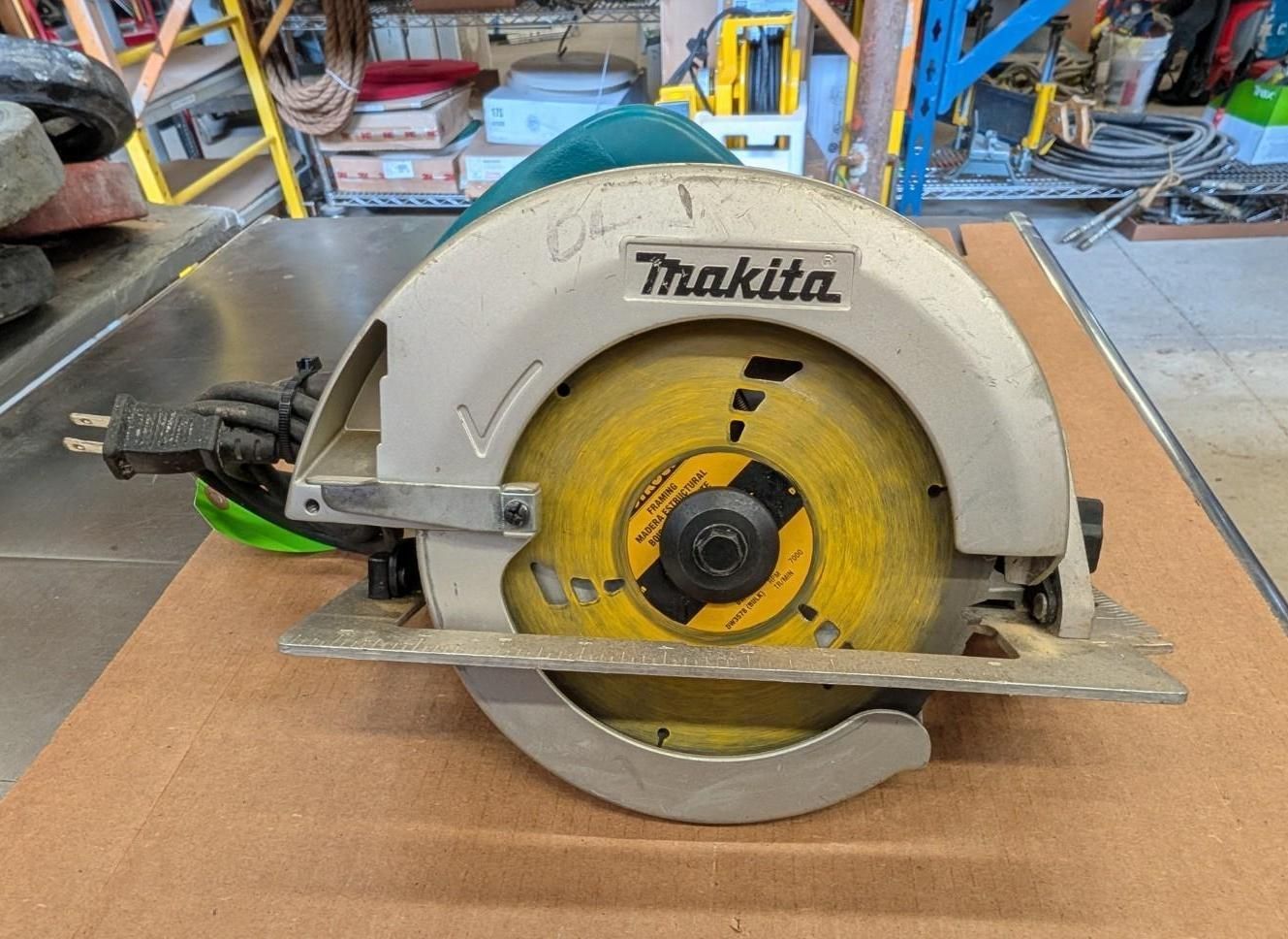 Makita circular saw on a workbench in a workshop, with a yellow blade and gray housing