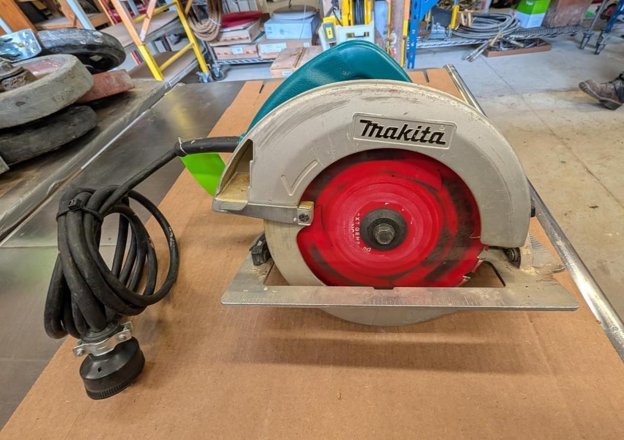 Makita circular saw with red blade on a workbench in a workshop