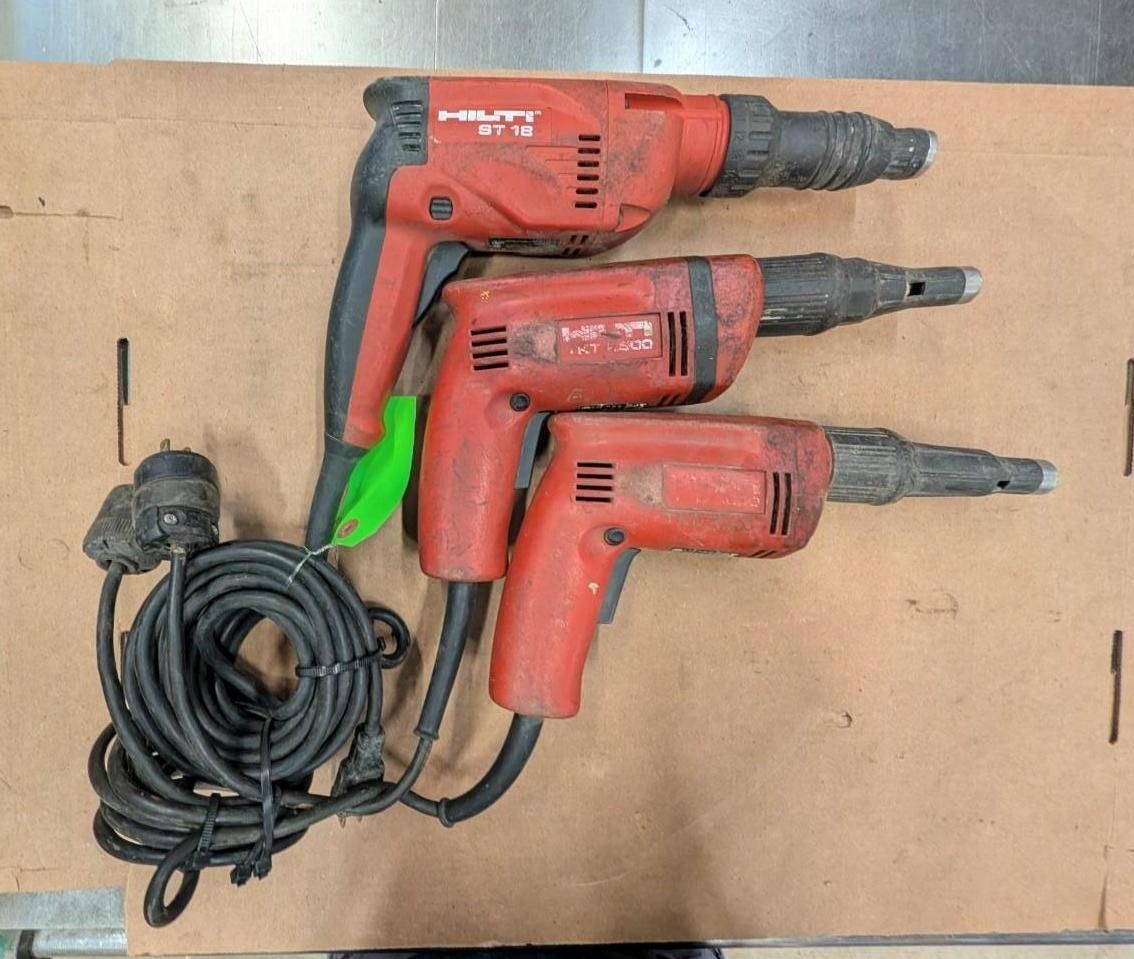 Three red power drills with coiled black cords on a cardboard surface.