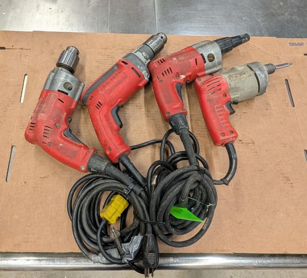 Four red corded power drills on a workbench, tangled black cords in front.