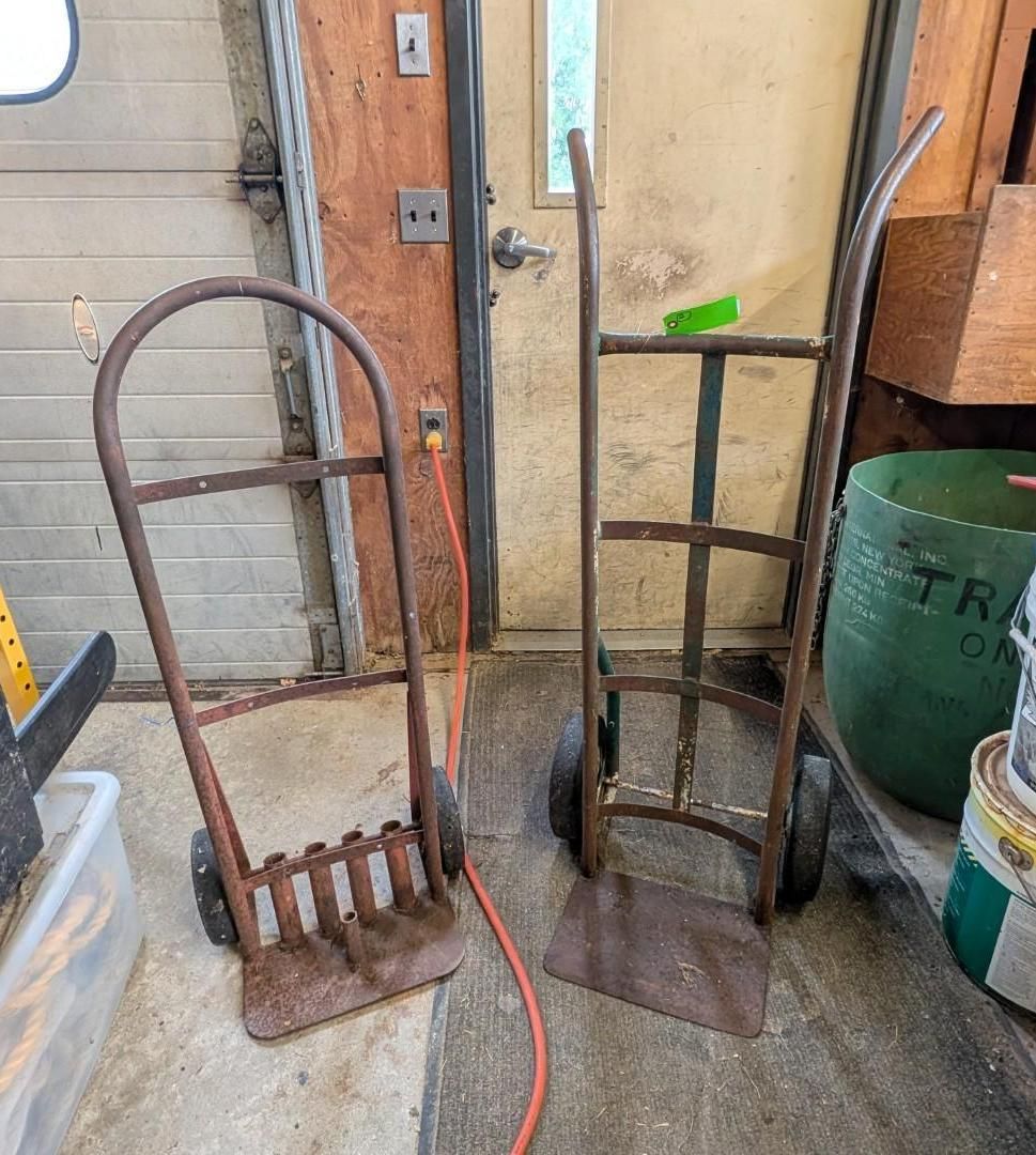Two hand trucks leaning against a garage wall near a door