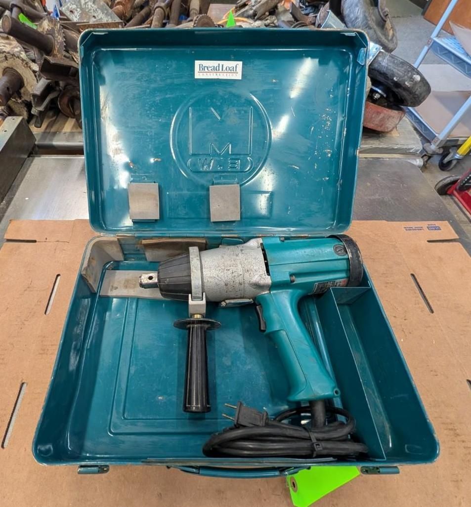Blue metal tool case with an electric impact wrench and cord inside, sitting open on a workbench.