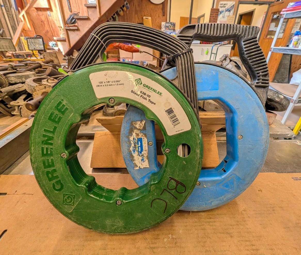 Two large reel spools, one green and one blue, stacked in a workshop