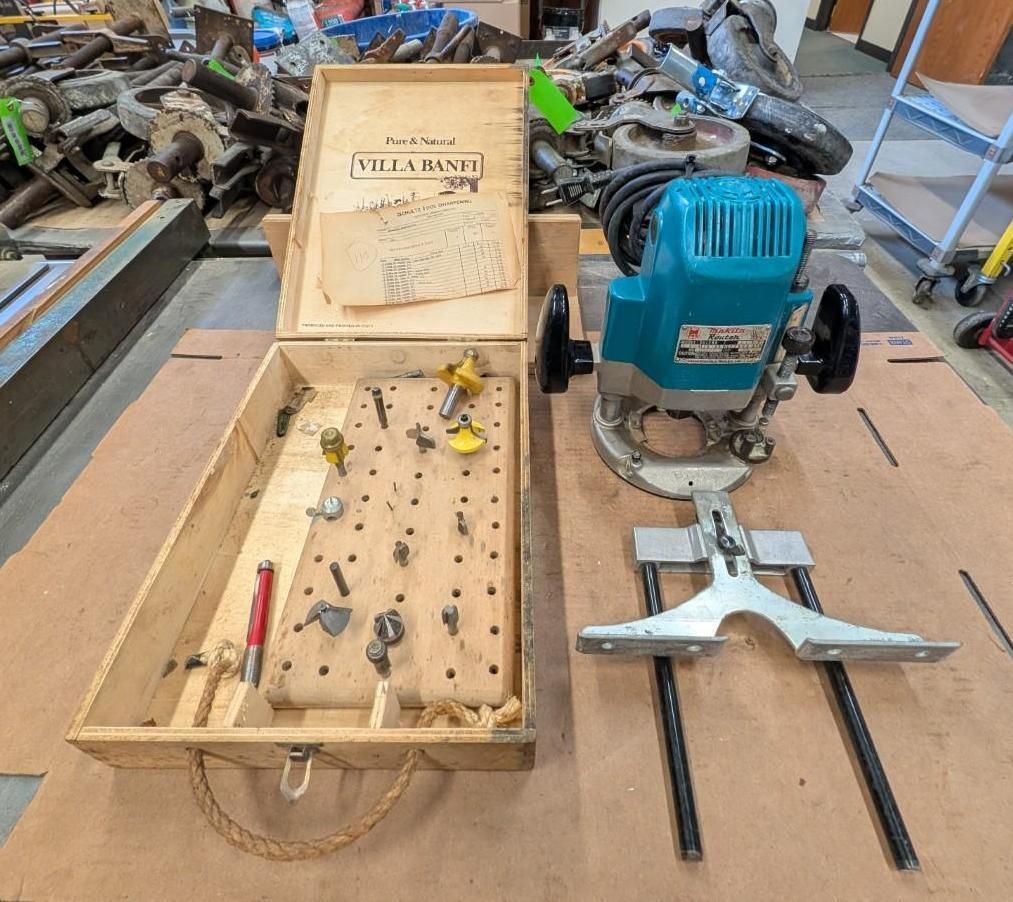 Woodworking tools on a workbench, including a blue router, wooden box, and hand tools.