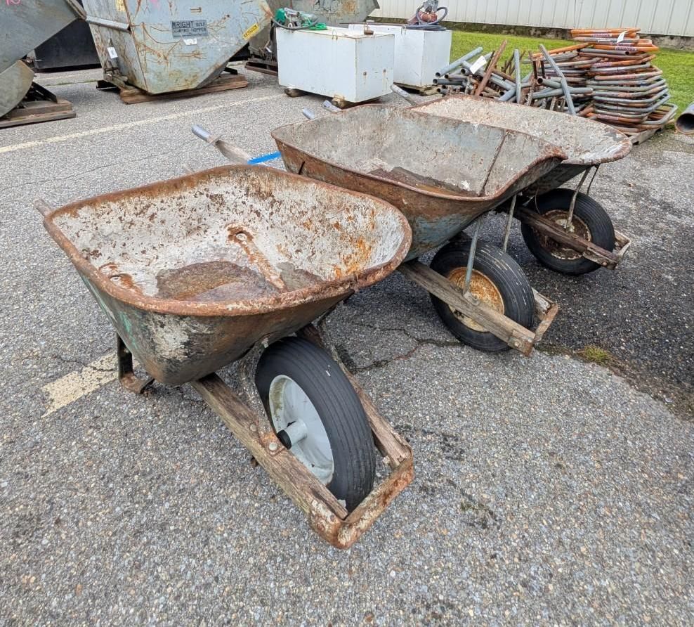 Two wheelbarrows with tires on an outdoor gravel lot.