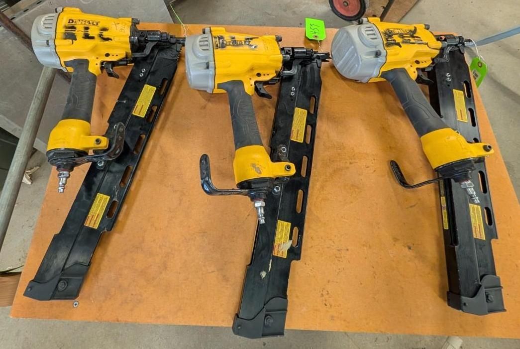Three yellow pneumatic nail guns laid on a wooden workbench, each with black magazines and silver tops