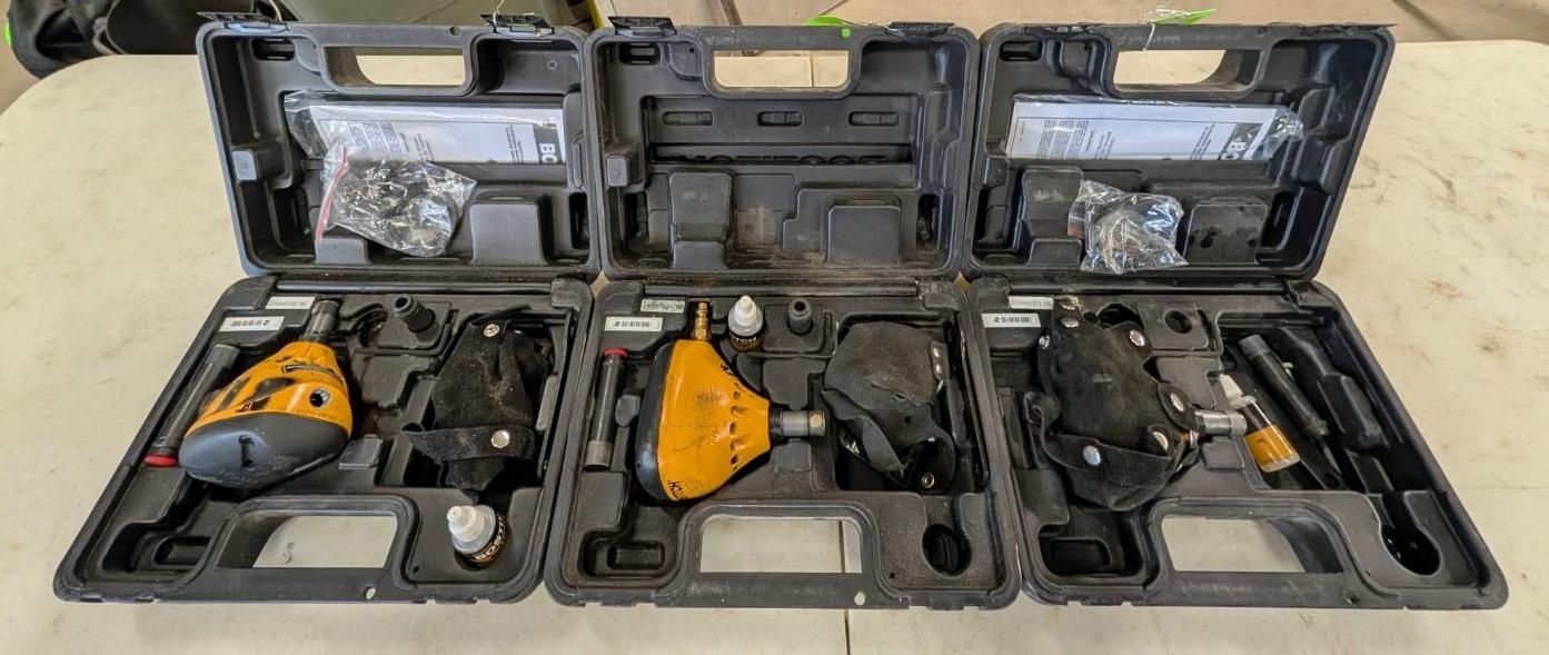 Open black cases holding three yellow-and-black power tools on a beige surface