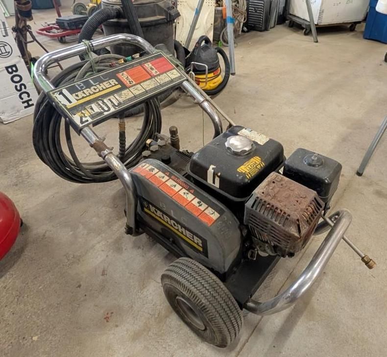 Black Bosch pressure washer on a wheeled frame in a garage or workshop.