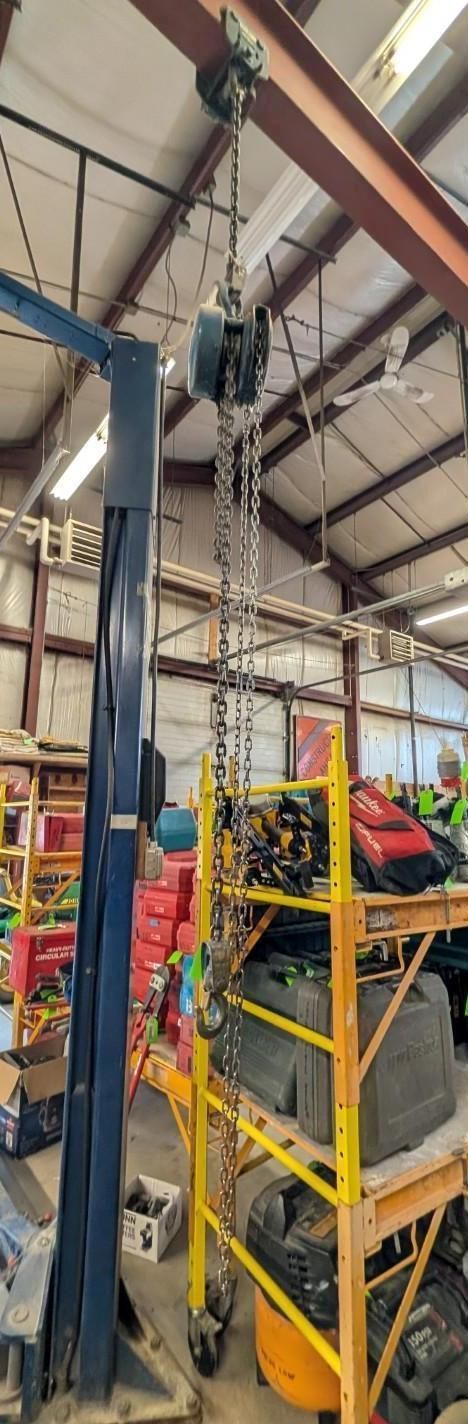 Warehouse aisle with stacked yellow carts, colorful tools, and overhead industrial beams