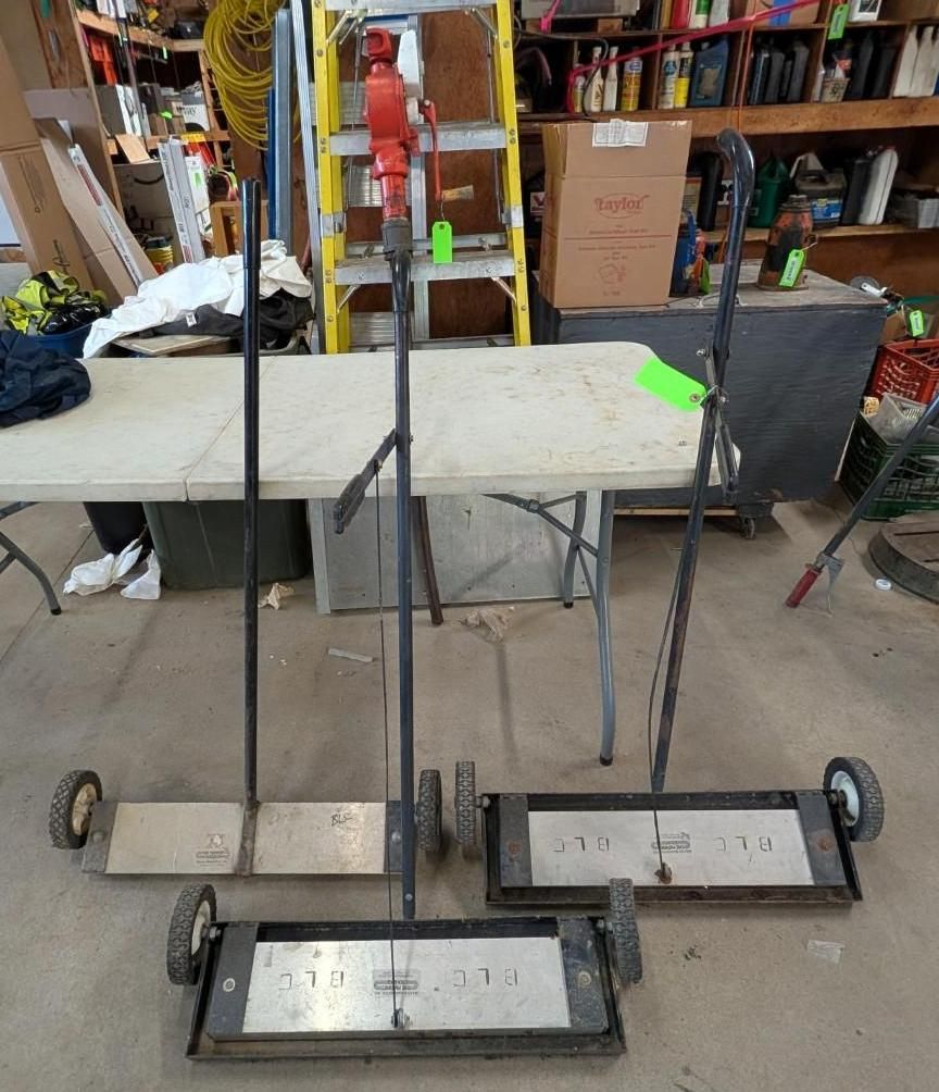 Four wheeled carts with vertical rods and labels in a workshop aisle, with shelves and boxes behind them