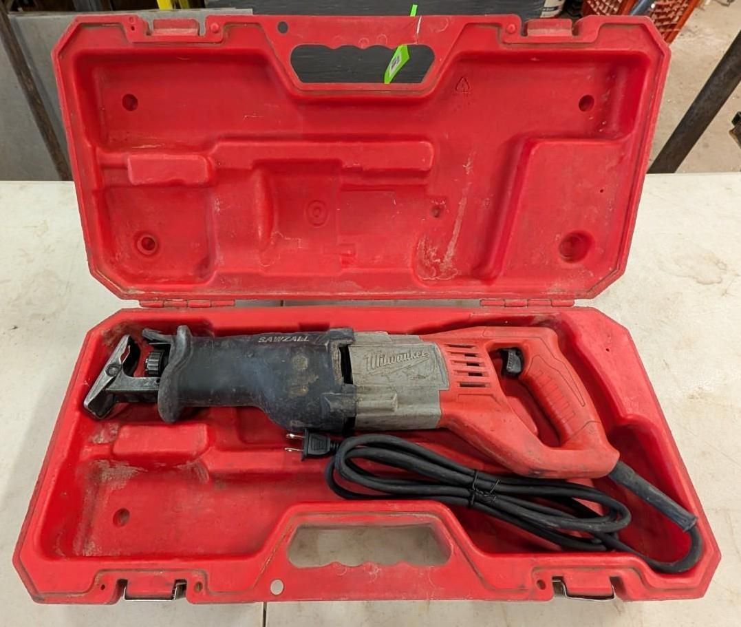 Open red carrying case holding a black and gray power saw with cord on a workbench.