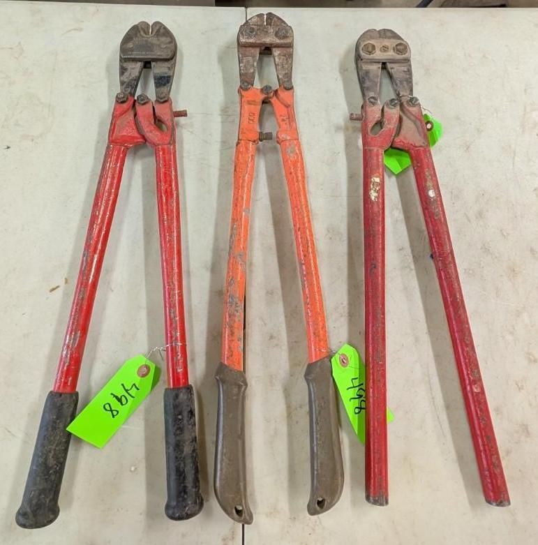 Three bolt cutters with red handles laid side by side on a table, with green tags attached.