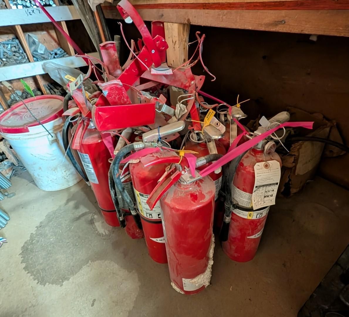 Several red fire extinguishers grouped in a storage area under a table
