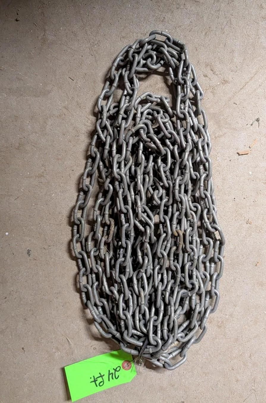 Coiled metal chain on a beige surface with a small green tag attached