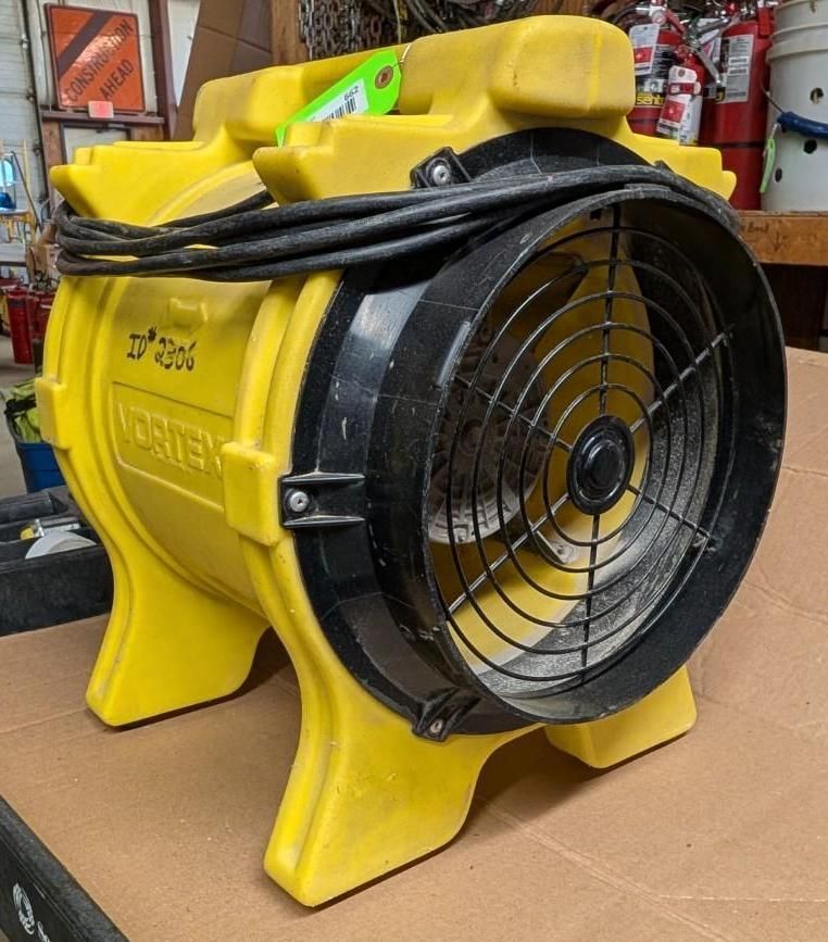 Yellow industrial blower fan with black grille and handle in a workshop setting
