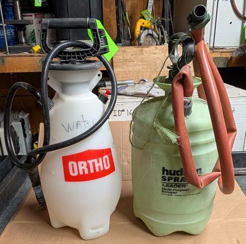 Two backpack sprayers, one white ORTHO and one green, standing in a garage.