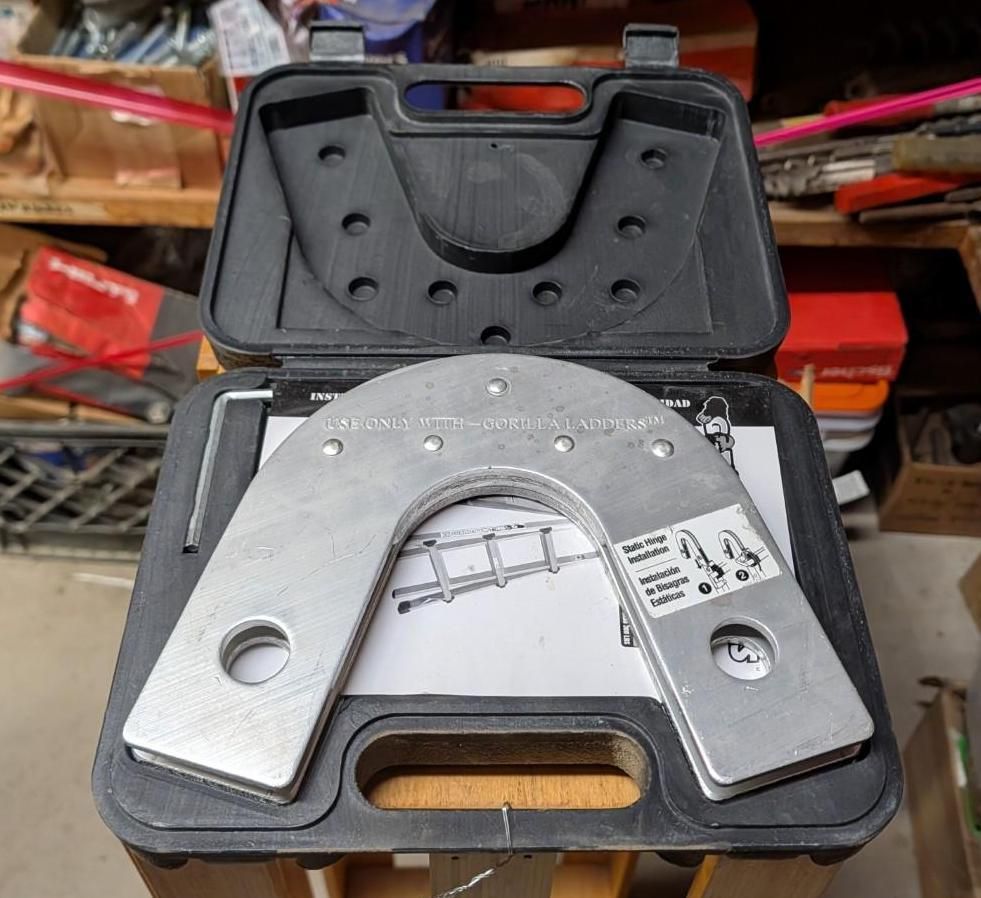 Open black case holding a silver metal U-shaped tool on a workbench