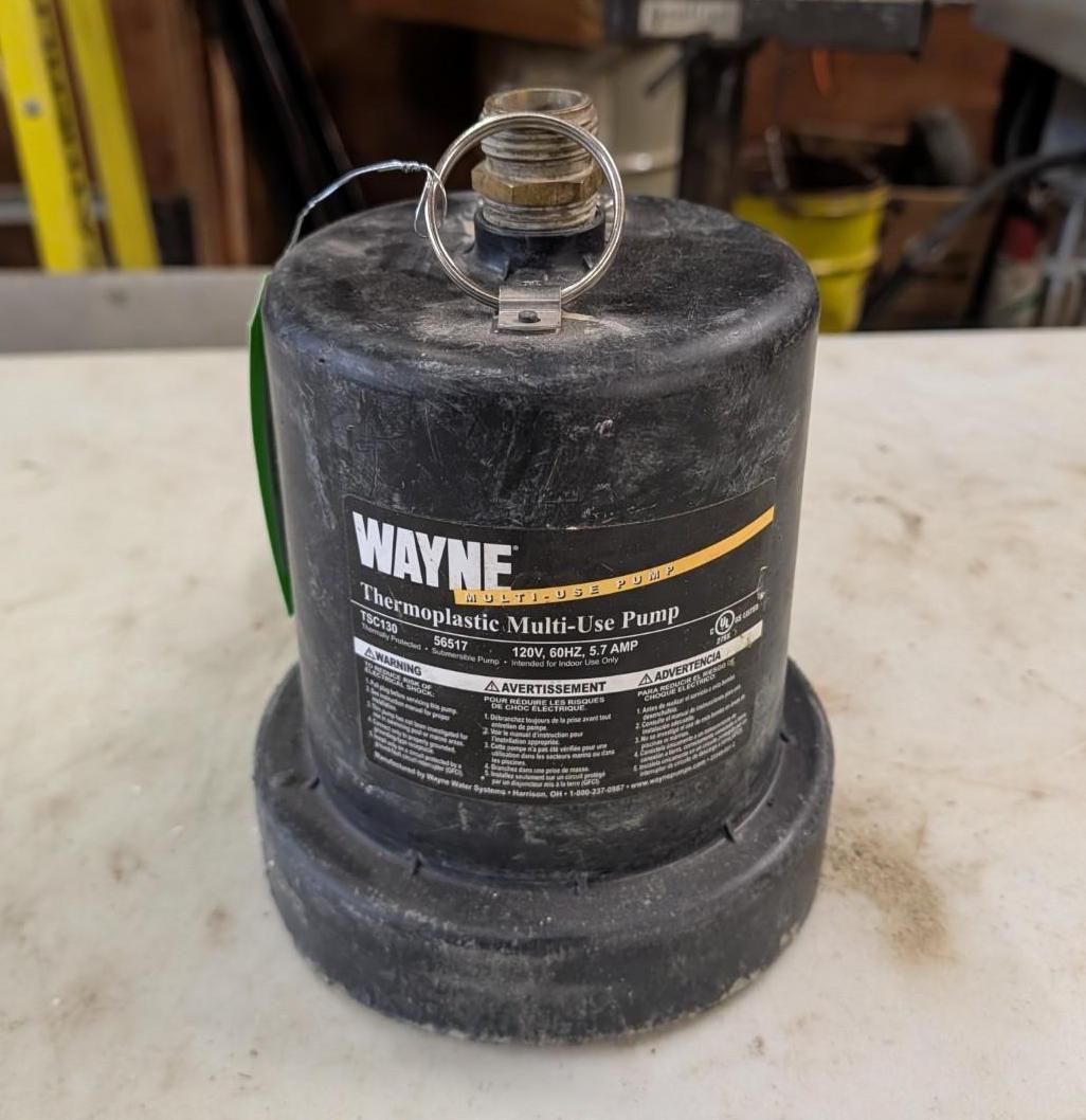Black Wayne fuel container with a white label on a workbench, shown in a workshop setting