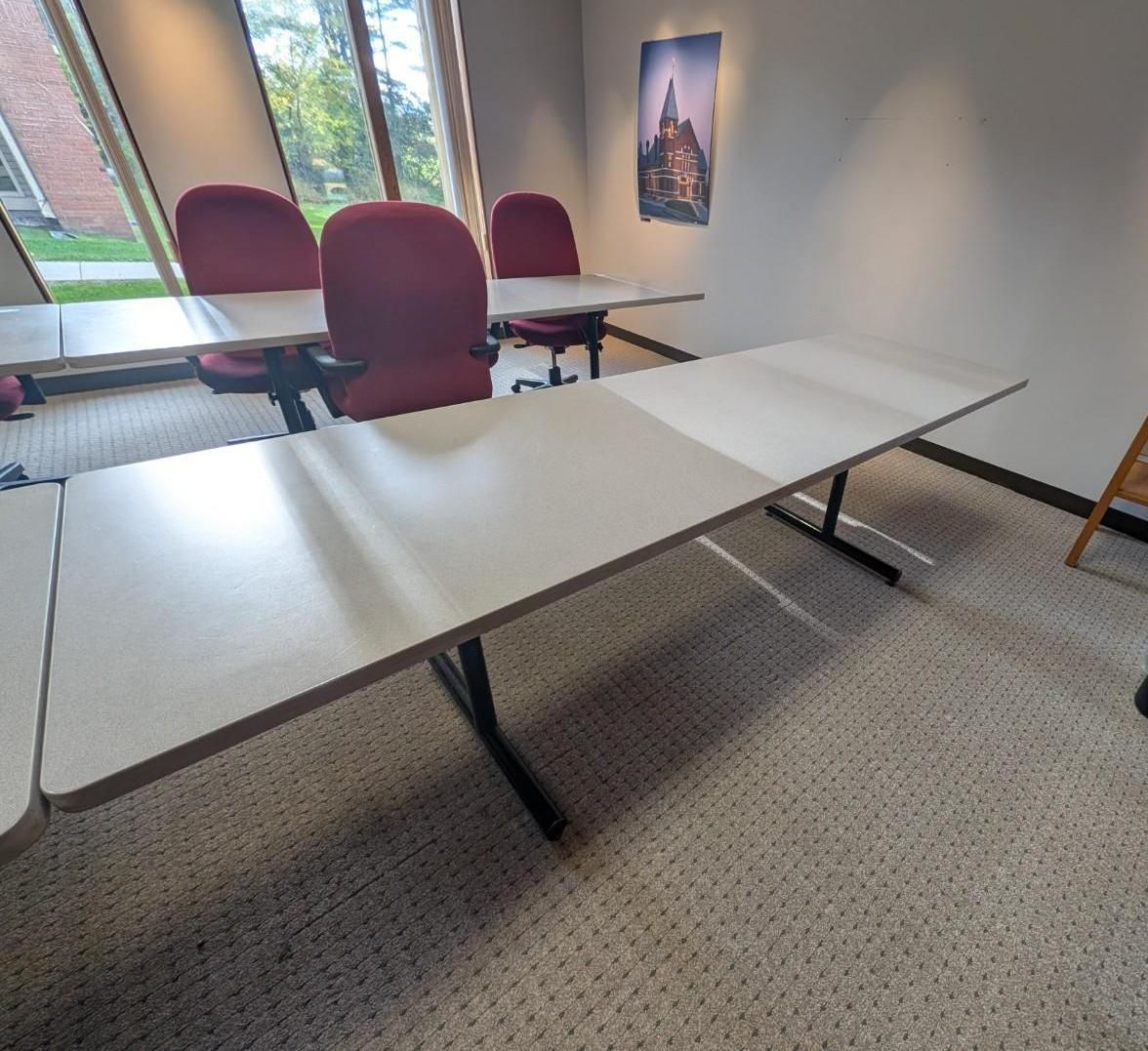 Conference room with folding tables and maroon chairs beside a window and wall art