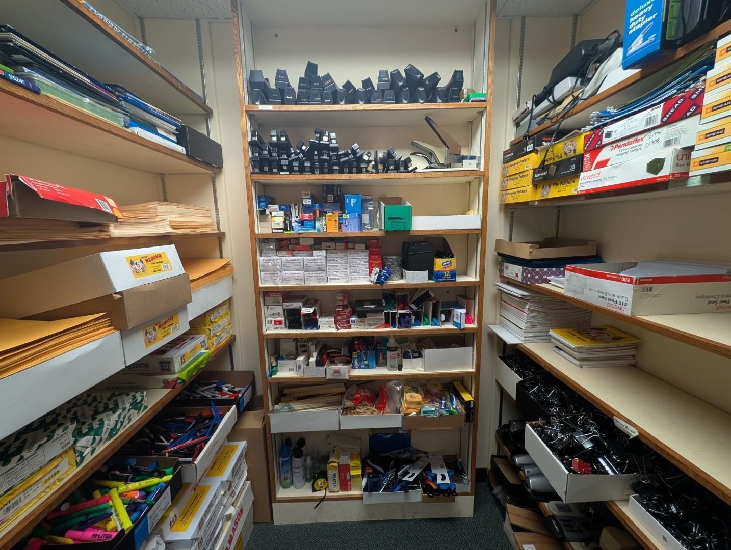 Narrow storage closet with shelves packed with assorted boxes, bins, and supplies.