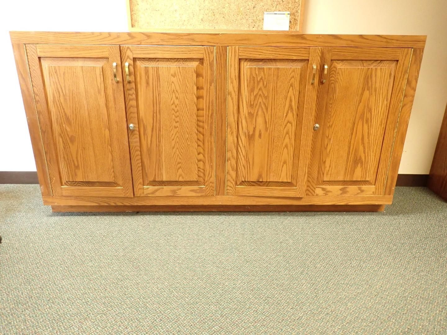Wooden four-door cabinet against a beige wall on carpeted floor