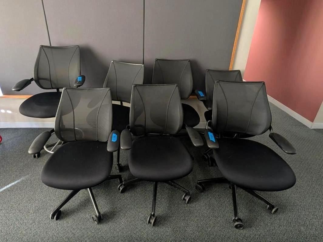 Black office chairs arranged in rows in a conference room with gray walls and a red accent wall