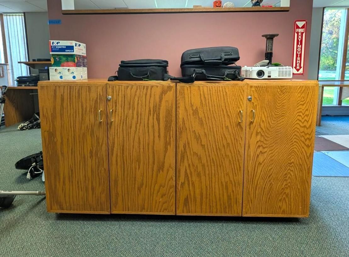 Wooden counter with black bags and a white device on top in a room with a red wall