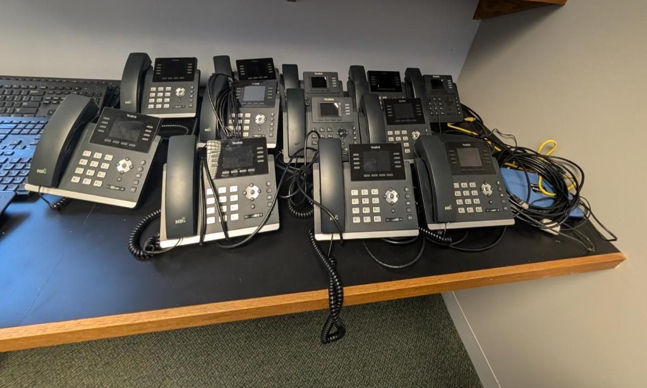 Several black office desk phones lined up on a tabletop