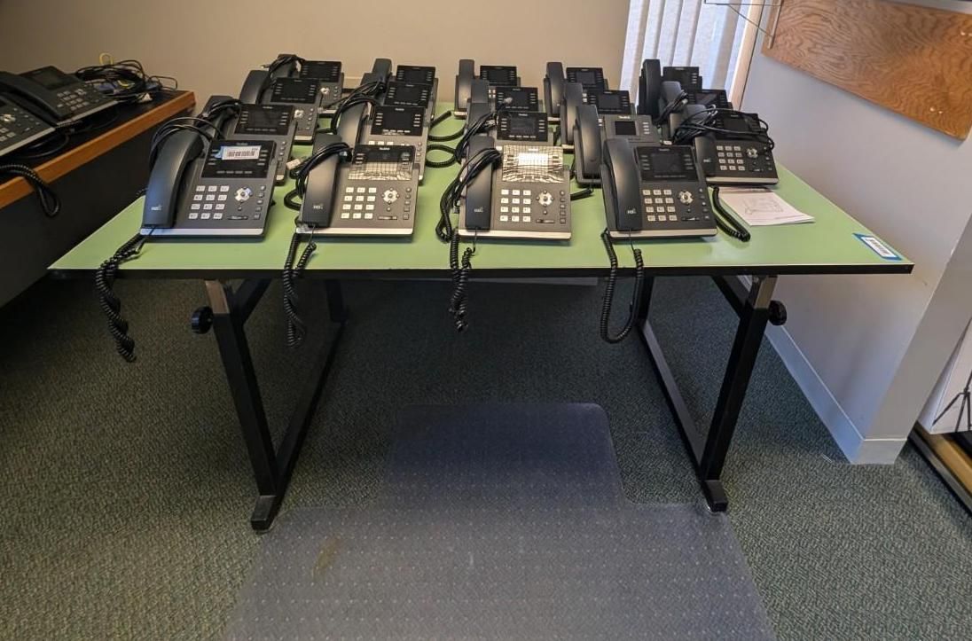 Several black desk phones arranged on tables in an office room