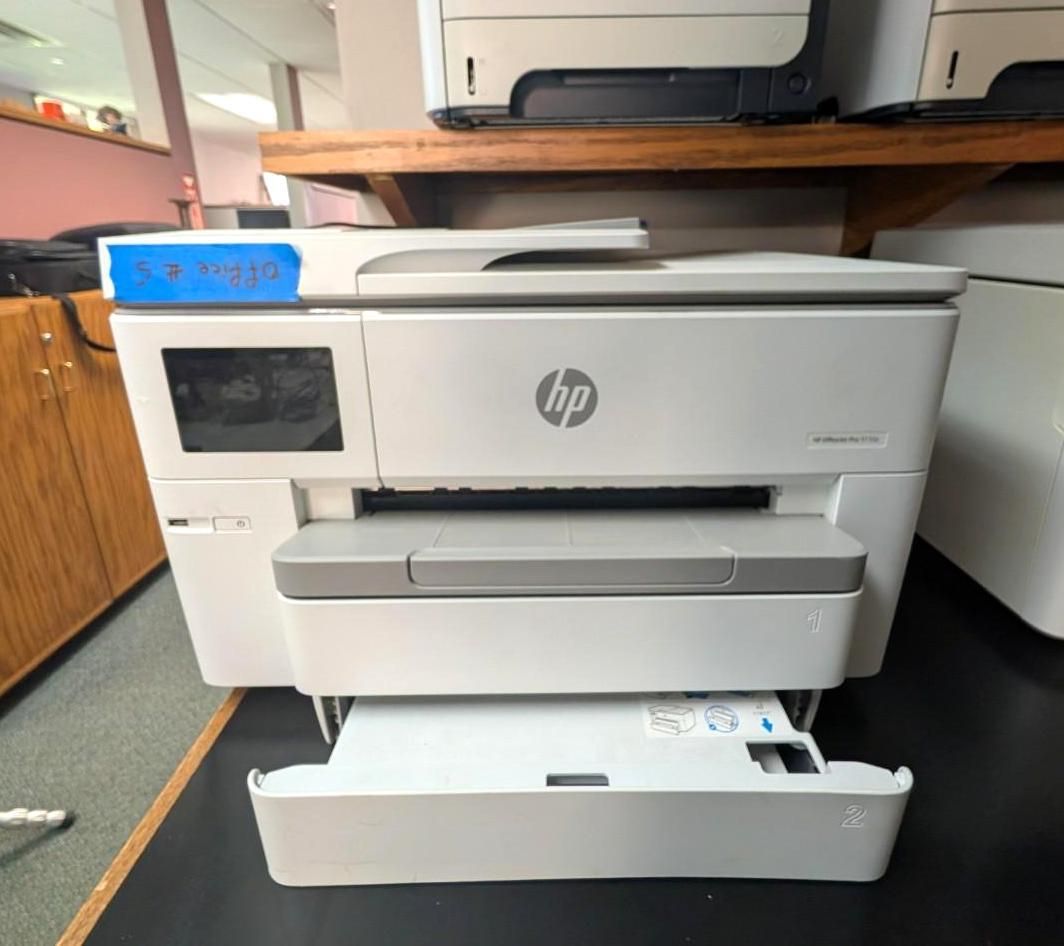White HP printer on a counter with paper tray open, in a kitchen or office setting