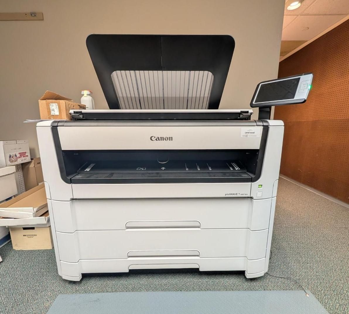 Canon office printer in a hallway, with paper tray open and touchscreen display raised