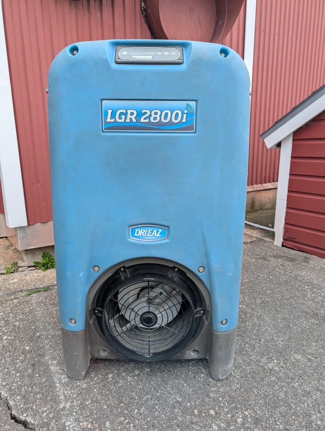 Blue LGR 2800 dehumidifier on a concrete floor beside red garage doors