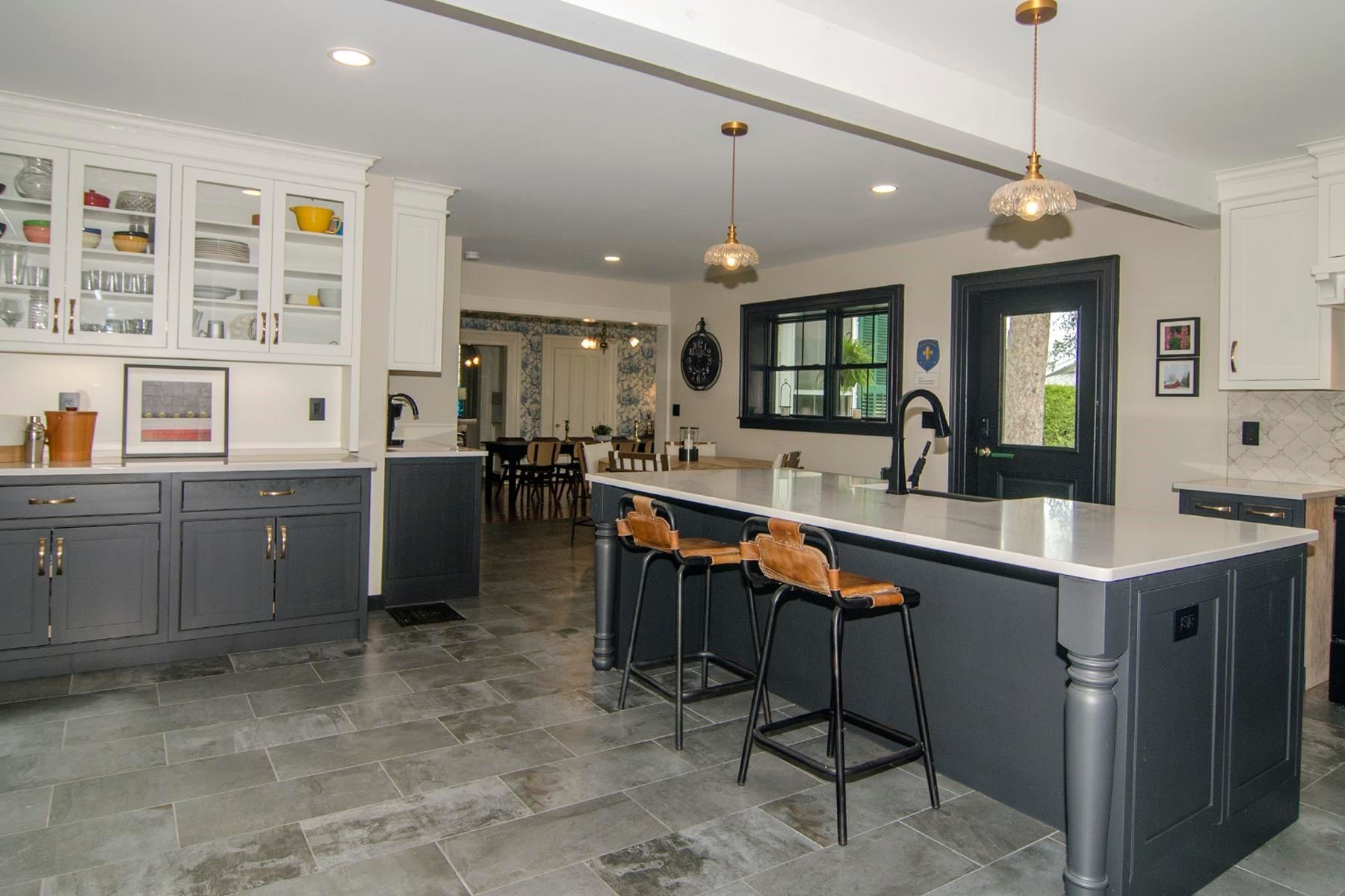 Modern kitchen with a dark gray island, white countertops, and bar stools.