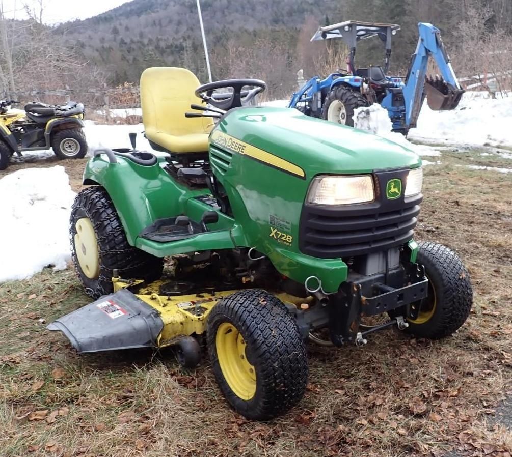 Green John Deere lawn tractor with mower deck parked on grass