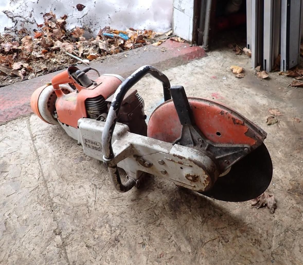 Orange concrete saw on floor near a wall and doorway.