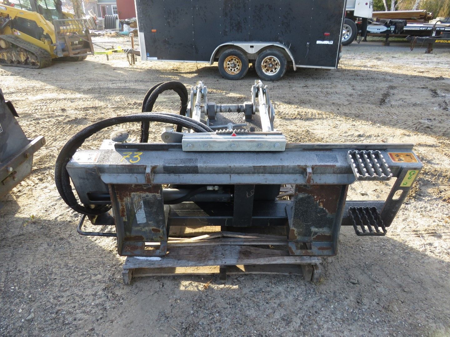 Heavy-duty metal machine attachment on a pallet in a gravel yard