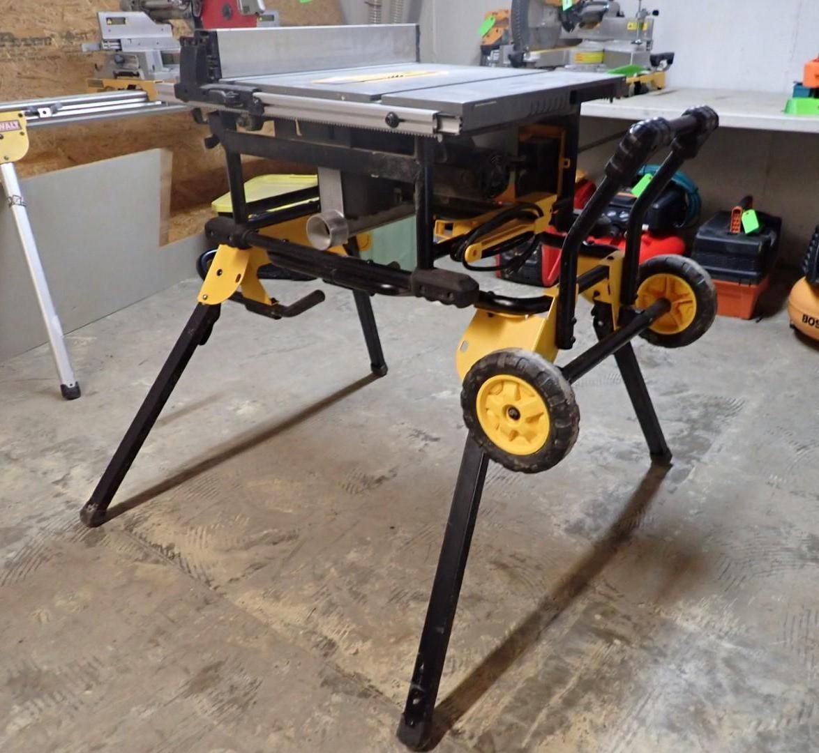 Black and yellow portable table saw on a wheeled stand in a workshop garage.