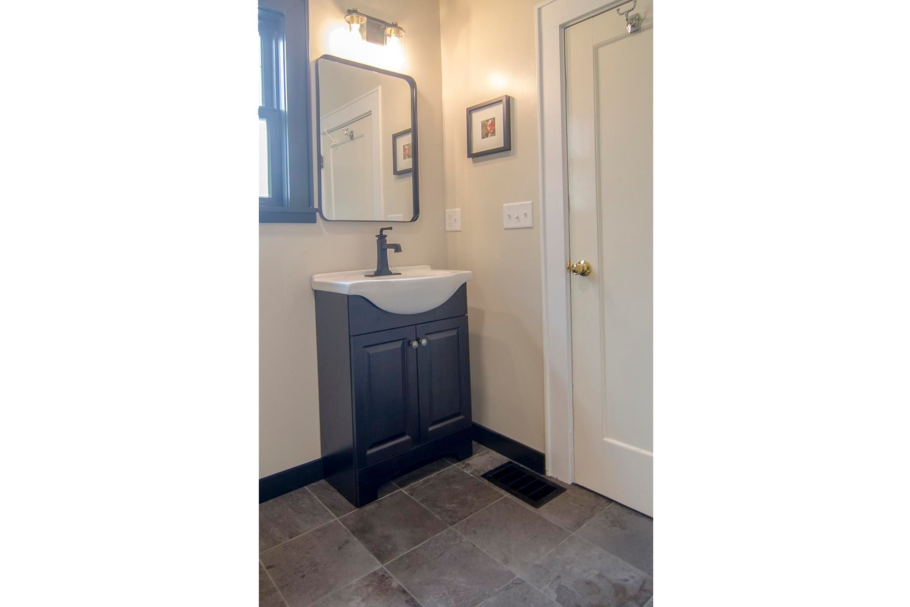 Bathroom with dark blue vanity, black-framed mirror, and white door.