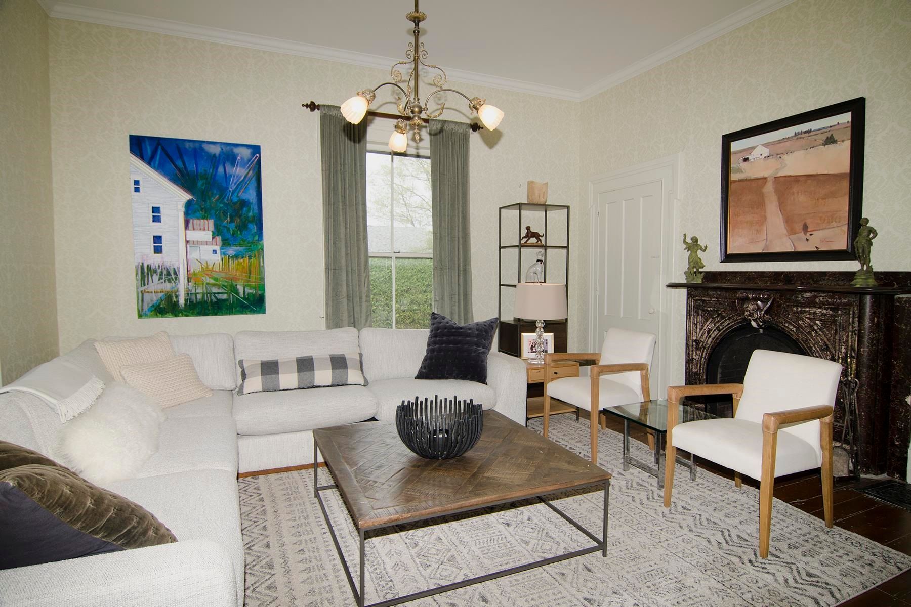 Living room with white sectional sofa, coffee table, two chairs, and a fireplace.