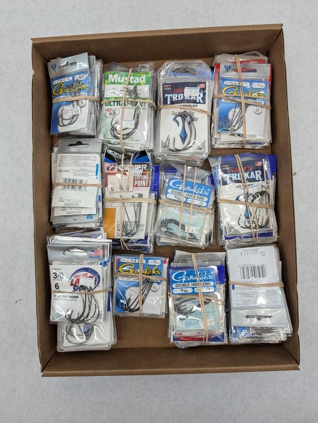 Open box filled with assorted packaged fishing hooks and tackle items.