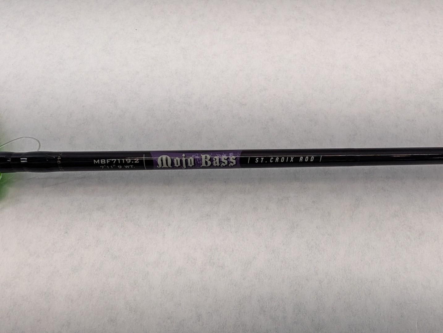 Black fishing rod with purple logo lying horizontally on a light surface.
