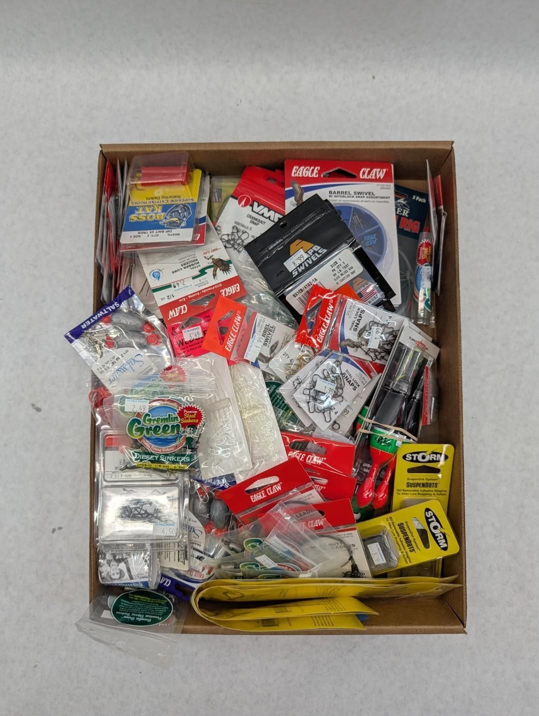 Open cardboard box filled with assorted small packaged items and tools in mixed colors.
