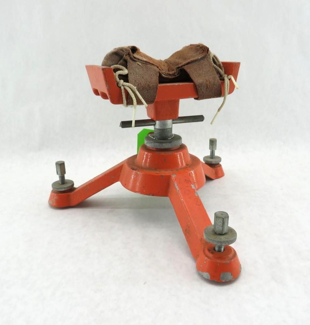 Orange tripod mount with a brown padded clamp on top, isolated on a white background