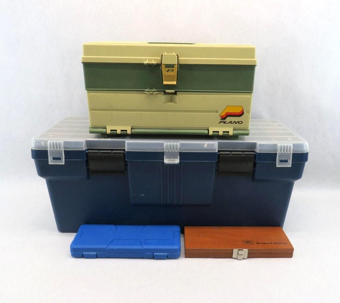 Three stacked plastic tackle boxes and two small cases, in blue, green, and brown, on a white background