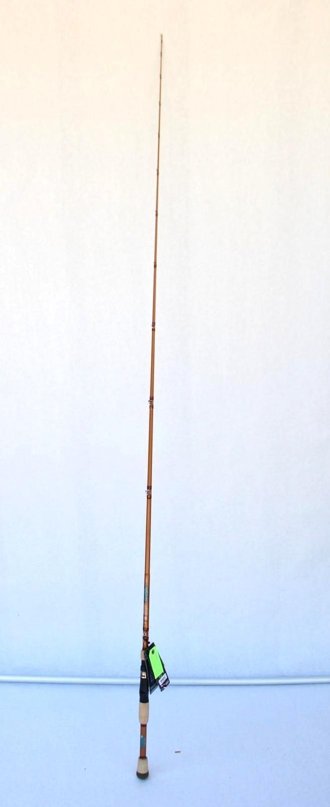 A tall fishing rod with a green reel standing upright against a plain wall.
