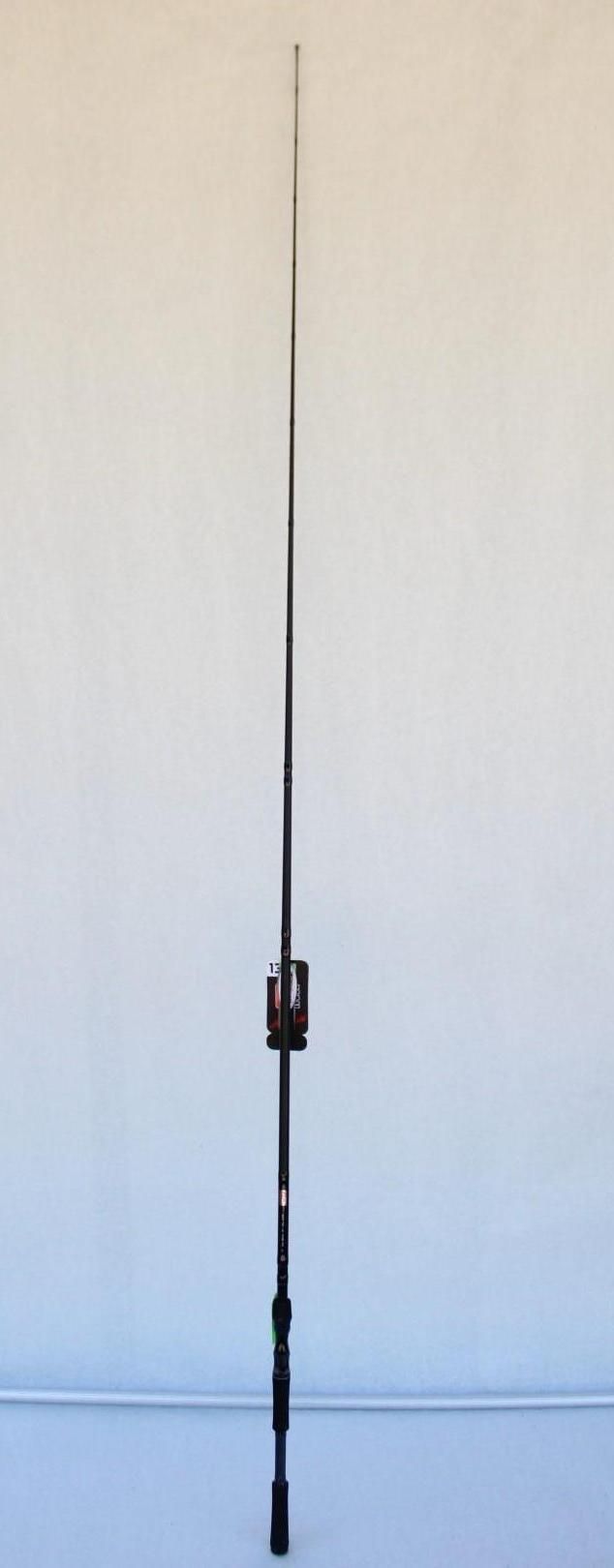 Tall black fishing rod standing upright against a plain wall.