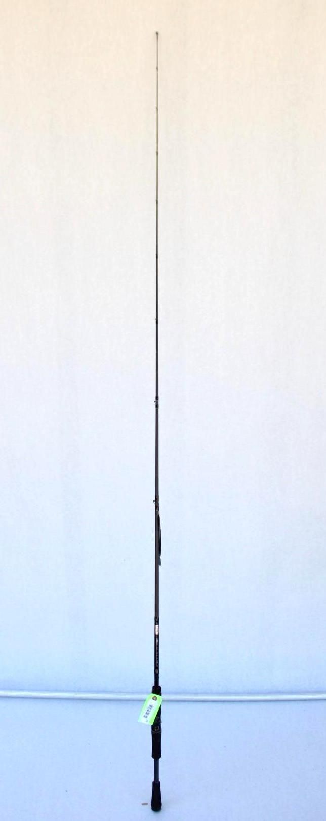 A tall fishing rod standing upright with a green reel against a plain white wall.