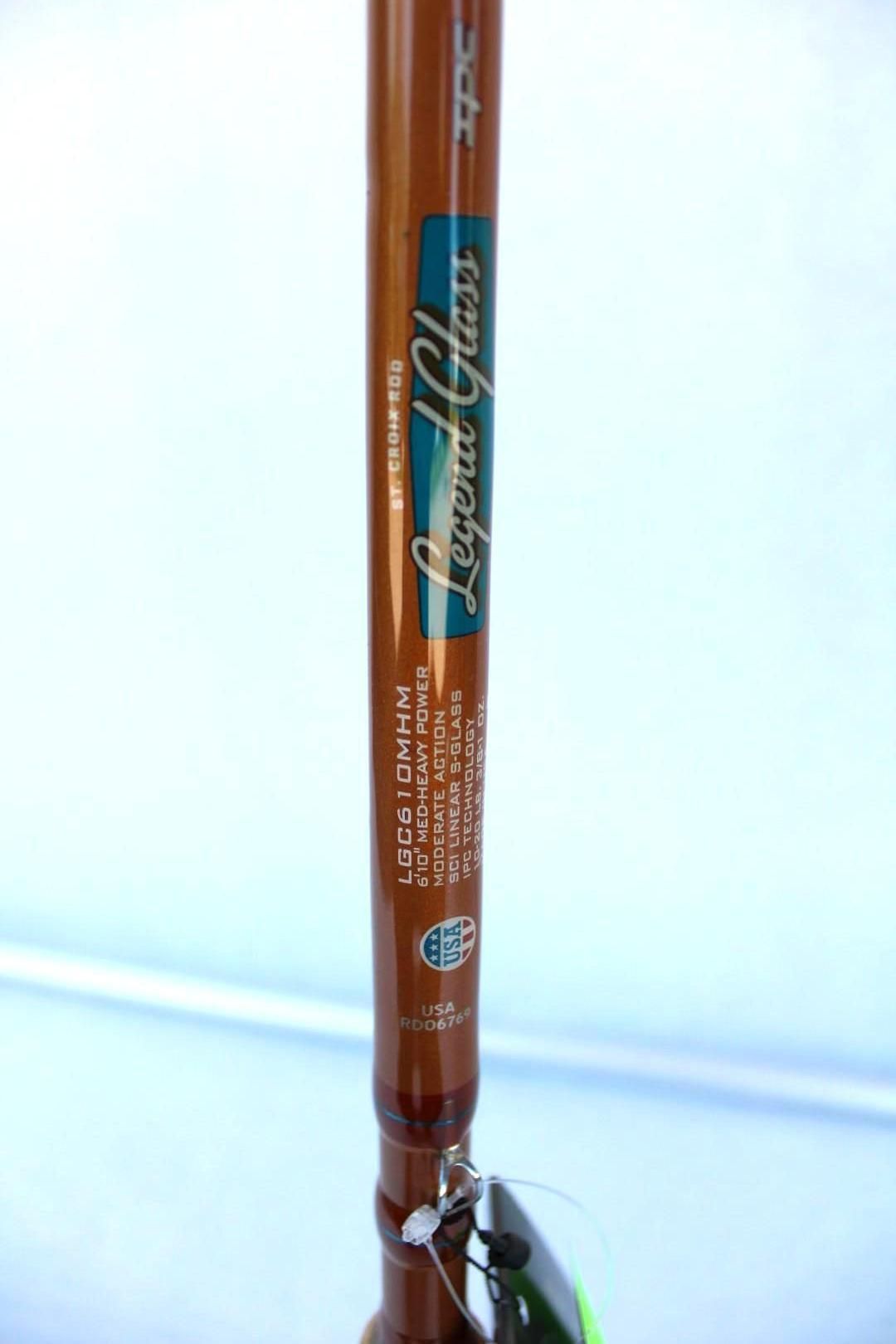 Brown vertical fishing rod with teal label standing in a clear holder against a light background