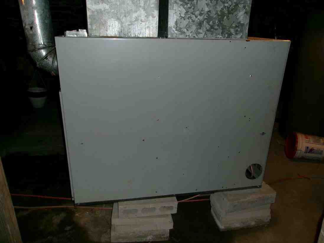 Gray metal panel mounted low on stacked blocks in an industrial setting