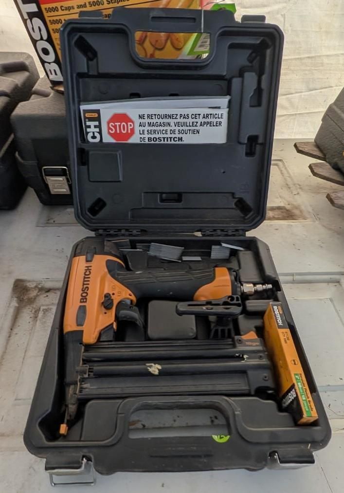 Open carrying case with an orange-and-black power tool and accessories inside on a brick surface